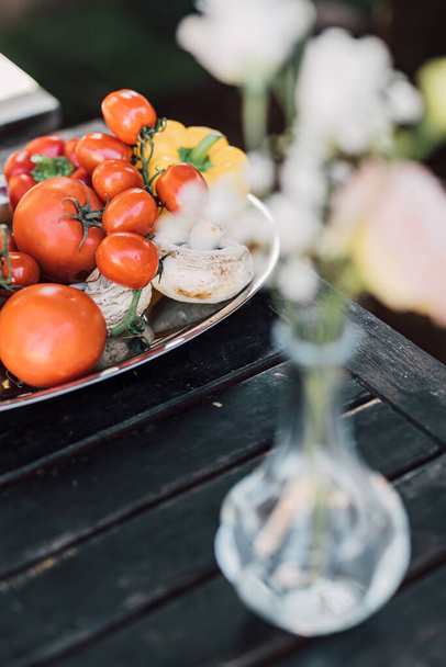 Variety of vegetables: tomatoes, pepper and mushrooms on a tray, standing on black wooden outdoor table, to be cooked on grill for a garden party. Selective focus. Healthy diet lifestyle. - Фото, изображение