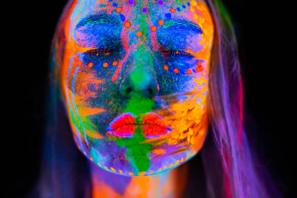 Beautiful young woman in neon light. Portrait of a model with fluorescent makeup posing in UV light with colorful makeup. - Fotoğraf, Görsel