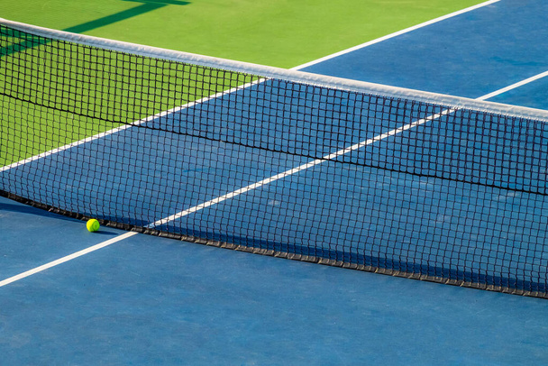 Kunstmatige tennisbaan. Zicht op de bal liggend aan het net. Zeer heldere kleuren - Foto, afbeelding
