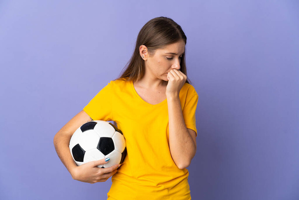 Young Lithuanian football player woman isolated on purple background having doubts - Foto, afbeelding