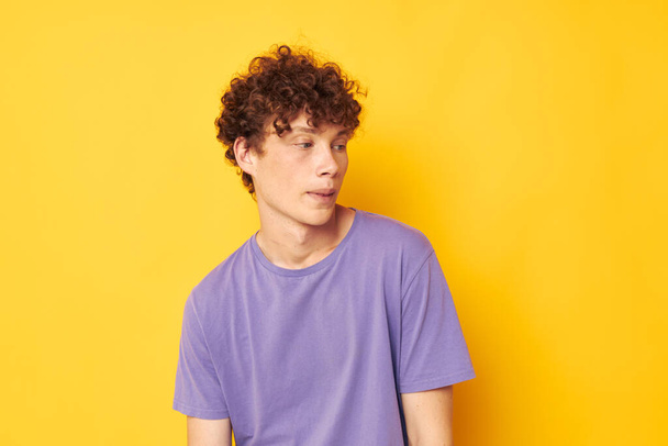guy with curly hair in purple t-shirts studio yellow background - Valokuva, kuva