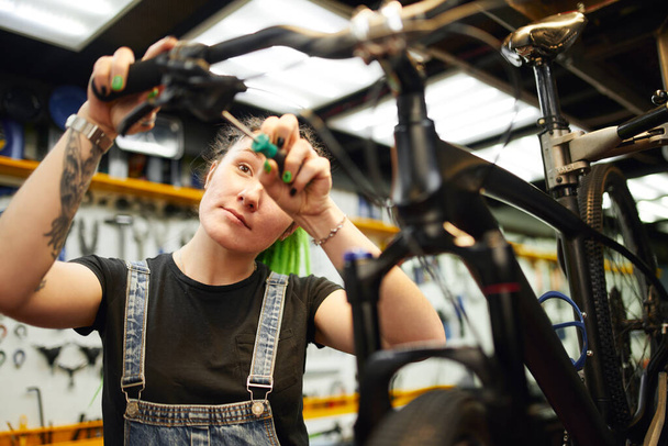 Content woman repairing bike in workshop - Fotografie, Obrázek