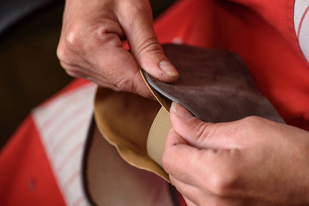 Shoemaker hands sewing the lining to the handmade leather shoe in workshop. Manufacturing of craft shoes. Small business concept - 写真・画像