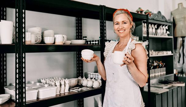 ¿Cuál te gusta? Retrato recortado de una atractiva mujer madura de pie y organizando su cerámica en un estante en su taller. - Foto, imagen