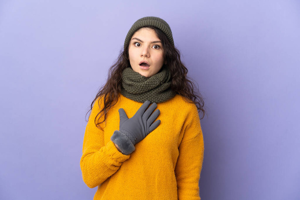 Teini venäläinen tyttö talvella hattu eristetty violetti tausta yllättynyt ja järkyttynyt katsoessaan oikealle - Valokuva, kuva