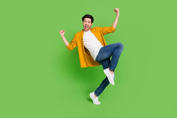 Full size photo of young happy crazy screaming guy raise fist in victory triumph isolated on green color background - Zdjęcie, obraz