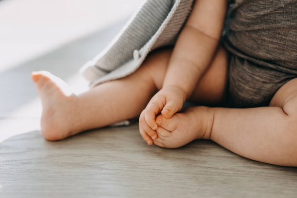 Primer plano de los pies descalzos de un bebé sentado en un suelo de parquet en casa. - Foto, Imagen
