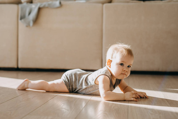 Barefoot baby kruipend op een parketvloer thuis.  - Foto, afbeelding