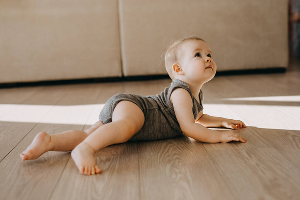 Bebé acostado boca abajo en el suelo en casa, mirando hacia arriba. - Foto, Imagen