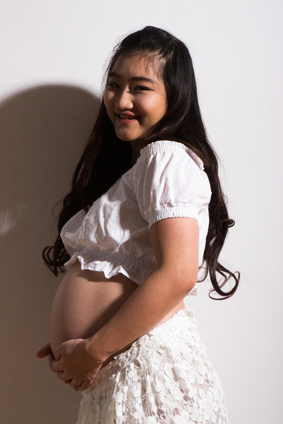 embarazada acariciando su vientre sobre fondo blanco - Foto, imagen