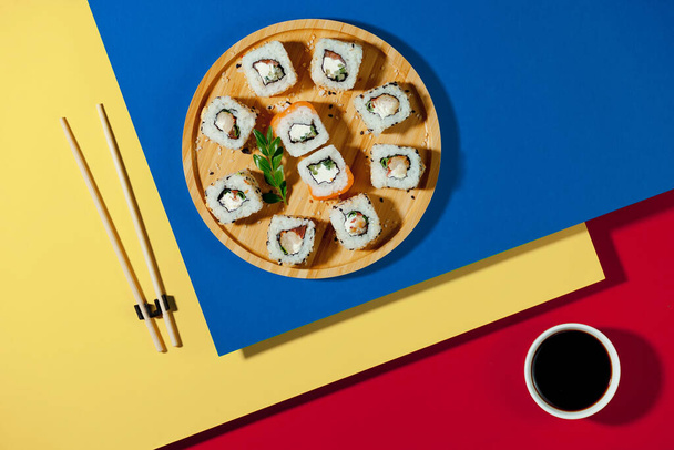 Sushi en un plato sobre un fondo brillante y colorido. - Foto, imagen