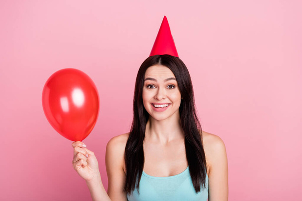 Photo of optimistic millennial birthday lady hold balloon wear hat blue top isolated on pink background - Foto, imagen