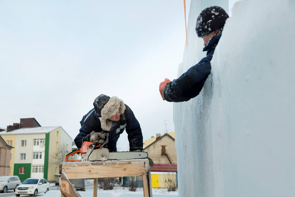 Dva pracovníci pokrývají rám dřevěné skluzavky s ledovými panely - Fotografie, Obrázek
