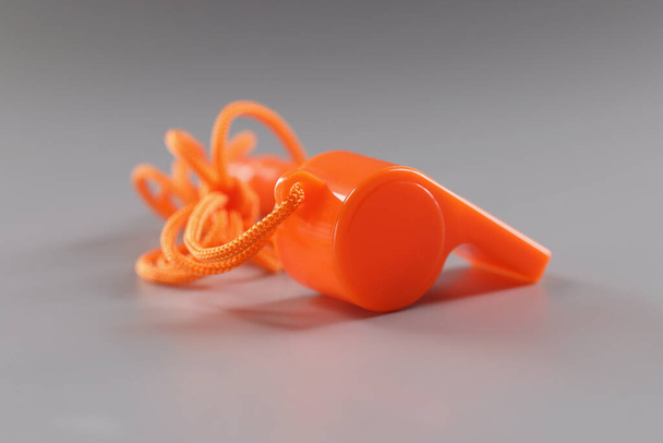 Oranžová sportovní píšťalka na šedém povrchu, nářadí pro školáky - Fotografie, Obrázek