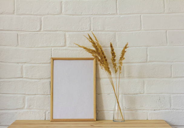 An empty photo frame and dried flowers in a vase on the table with a copy of the space.Scandinavian style - Photo, Image