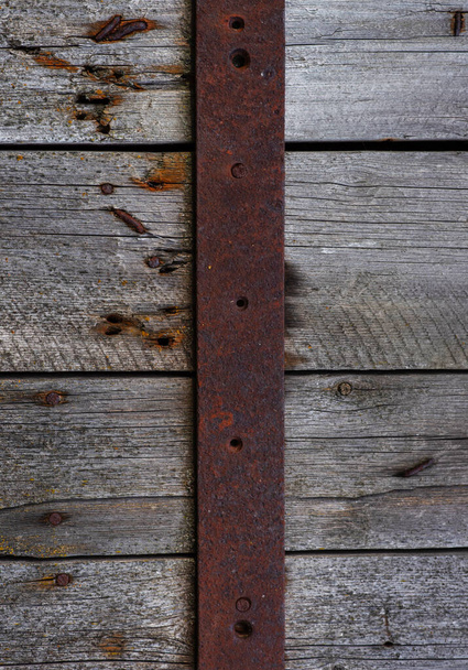 Old weathered wooden door with steel hinges. Distressed panels. Old wall texture background. Detail of an old wooden door with rusty door latch. - Foto, Imagen