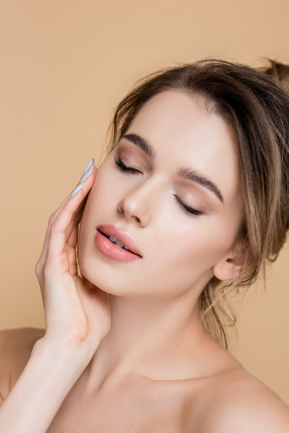 close up view of charming woman with closed eyes touching face isolated on beige - Foto, Bild