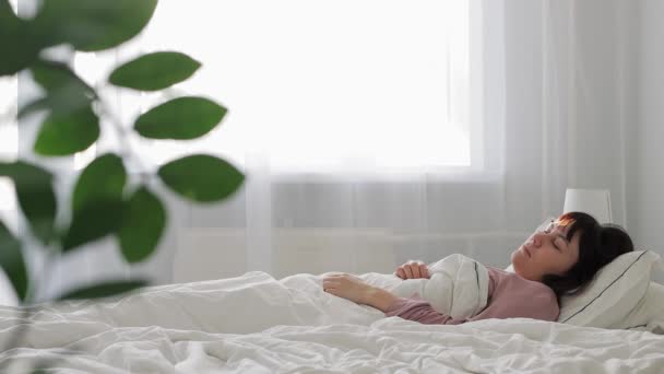 Guten Morgen Konzept - junge, fröhliche Frau wacht auf und schläft wieder ein  - Filmmaterial, Video