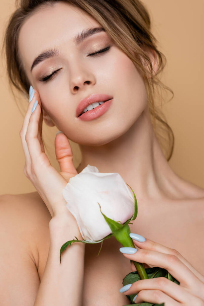 close up view of young woman with natural makeup near white rose isolated on beige - Fotó, kép