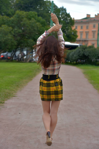 slender pretty brunette girl in a plaid blouse and skirt on a city street - Valokuva, kuva
