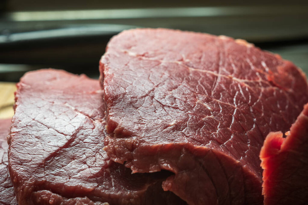surowe mięso z wołowiny w plasterkach na drewnianej desce do krojenia - Zdjęcie, obraz
