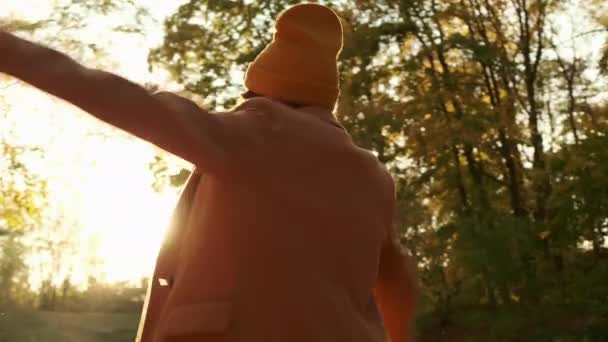 Mulher positiva em casaco e chapéu quente vira na floresta ensolarada - Filmagem, Vídeo