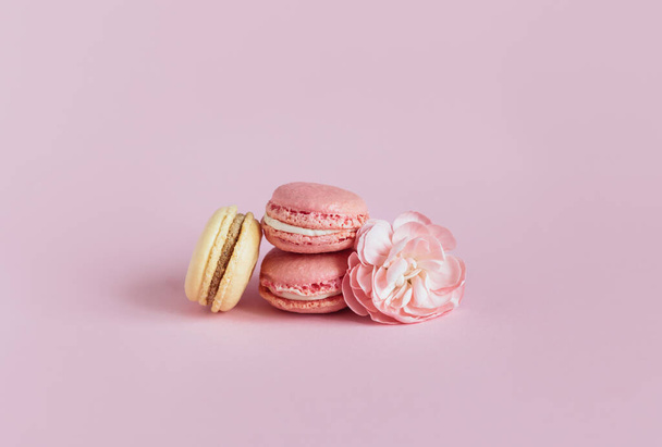 Tasty french macaroons with flowers on a pink pastel background.  Place for text. - Fotó, kép