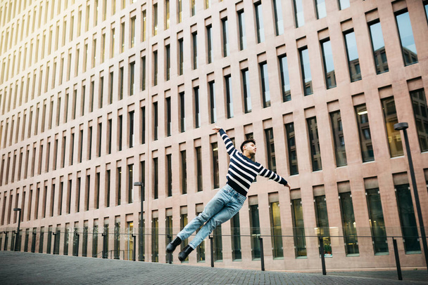 Молодий чоловік стрибає на вулиці
 - Фото, зображення