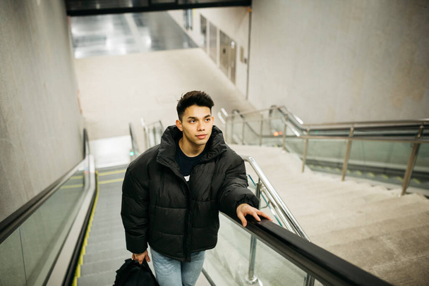 Νεαρός βγαίνει από το σταθμό του μετρό στις κυλιόμενες σκάλες - Φωτογραφία, εικόνα