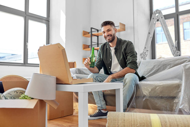 man with box of pizza and beer bottle at new home - Foto, Bild