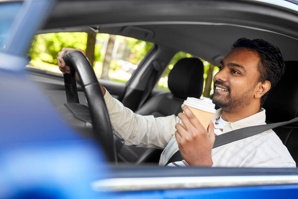 happy indian man or driver with coffee driving car - Foto, afbeelding
