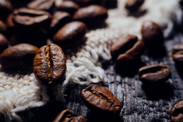 Kahve çekirdeklerinin makrofotoğrafçılığı ahşap ve çuval bezi üzerine kuruludur. Taze hasat aromatik kahve. Seçici Odaklanma. - Fotoğraf, Görsel