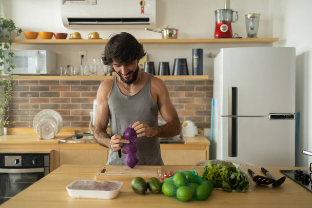 Happy and healthy young man meal prepping whole vegetarian meal in the kitchen. High quality photo. Feel good, healthy and health concept.  - Fotoğraf, Görsel
