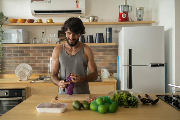 Happy and healthy young man meal prepping whole vegetarian meal in the kitchen. High quality photo. Feel good, healthy and health concept.  - Foto, Imagem
