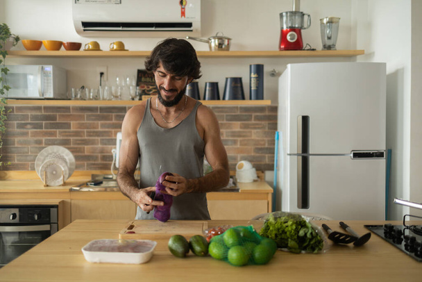 Happy and healthy young man meal prepping whole vegetarian meal in the kitchen. High quality photo. Feel good, healthy and health concept.  - Photo, Image
