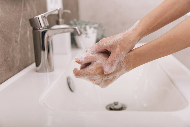 Washing hands under the flowing water tap. Hygiene concept hand detail. Washing hands rubbing with soap for corona virus prevention, hygiene to stop spreading corona virus in or public wash room - Foto, Imagem