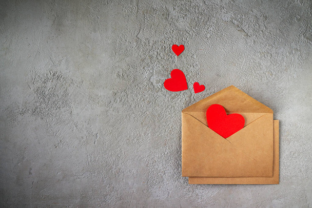craft envelopes with red paper hearts on gray plaster, copy space - Photo, image