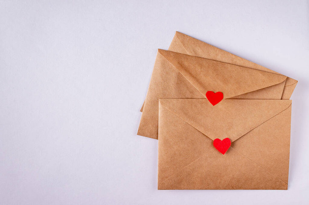 craft envelopes with red paper hearts on white background, copy space - Fotó, kép