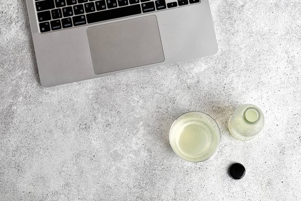 Glass and bottle of lemonade on the table with a laptop. Top view. Minimalism. Working time. Distant work - Zdjęcie, obraz