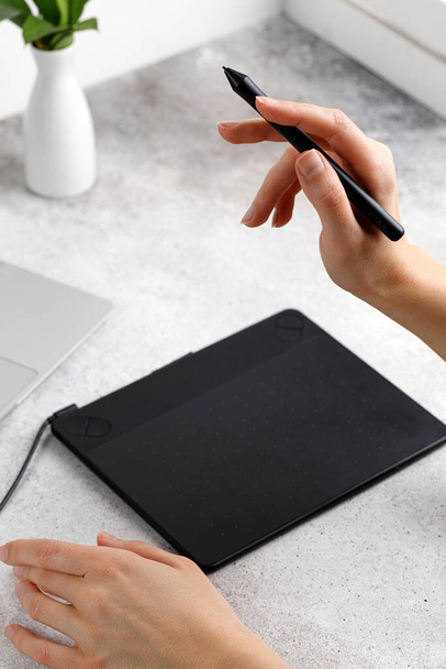 Kädet käyttämällä graafinen tabletti ja kannettava tietokone istuessaan pöydässä. Työskentelen projektin parissa. Kaukaista työtä. Suunnittelija tai valokuvaaja - Valokuva, kuva