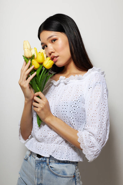 Charming young Asian woman with a bouquet of flowers smile close-up light background unaltered - Photo, Image