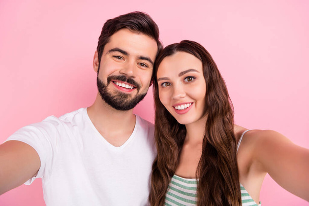 Photo of optimistic young brown hair couple do selfie wear white t-shirt dress isolated on pink color backgound - Zdjęcie, obraz