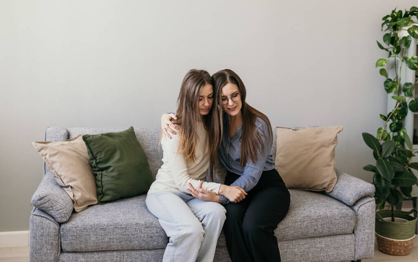 Psychological assistance to women. Domestic violence. Two women are sitting on the couch and hugging. Supportive hugs - Photo, Image