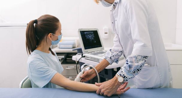 Doctor doing the ultrasound on the hand close up. Doctor demonstrates results of ultrasound to patient. Medical ultrasound scan. Rehabilitation application injection for muscle relaxation - Foto, imagen