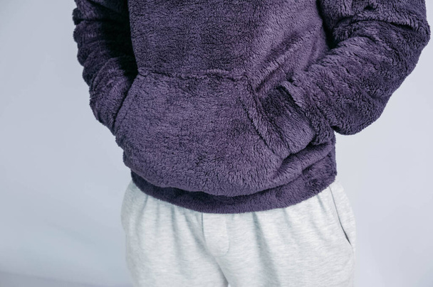 Egy fiatal férfi portréja, lila pulóverben, kapucnival, fehér háttérrel. Másolás, üres hely a szövegnek - Fotó, kép