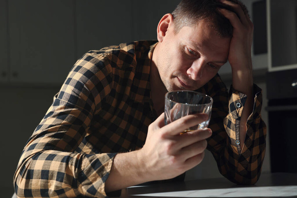 Addicted man with alcoholic drink at table in kitchen - Photo, image