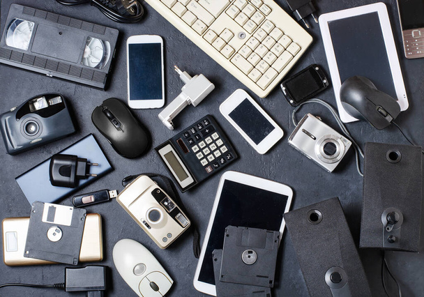 Old electronic devices on a dark background. The concept of recycling and disposal of electronic waste - Photo, Image