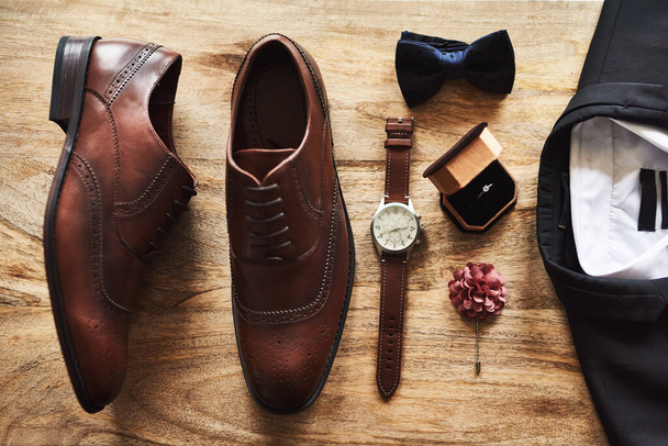 All set for the big day. Still life shot of formal shoes alongside a suit and other accessories on a wooden surface. - Foto, Imagen