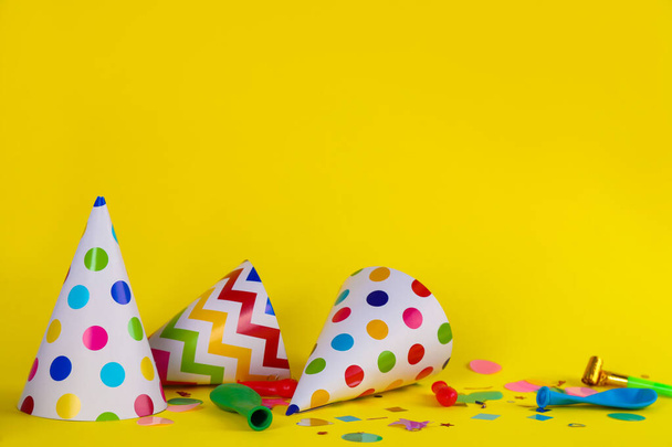 Colorful party hats and other festive items on yellow background. Space for text - Foto, immagini