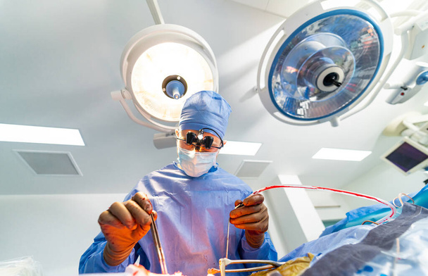 Нейрохирург в специальных хирургических очках обеспечивает операцию. Внимательный, внимательный доктор в операционной. Крупный план. - Фото, изображение